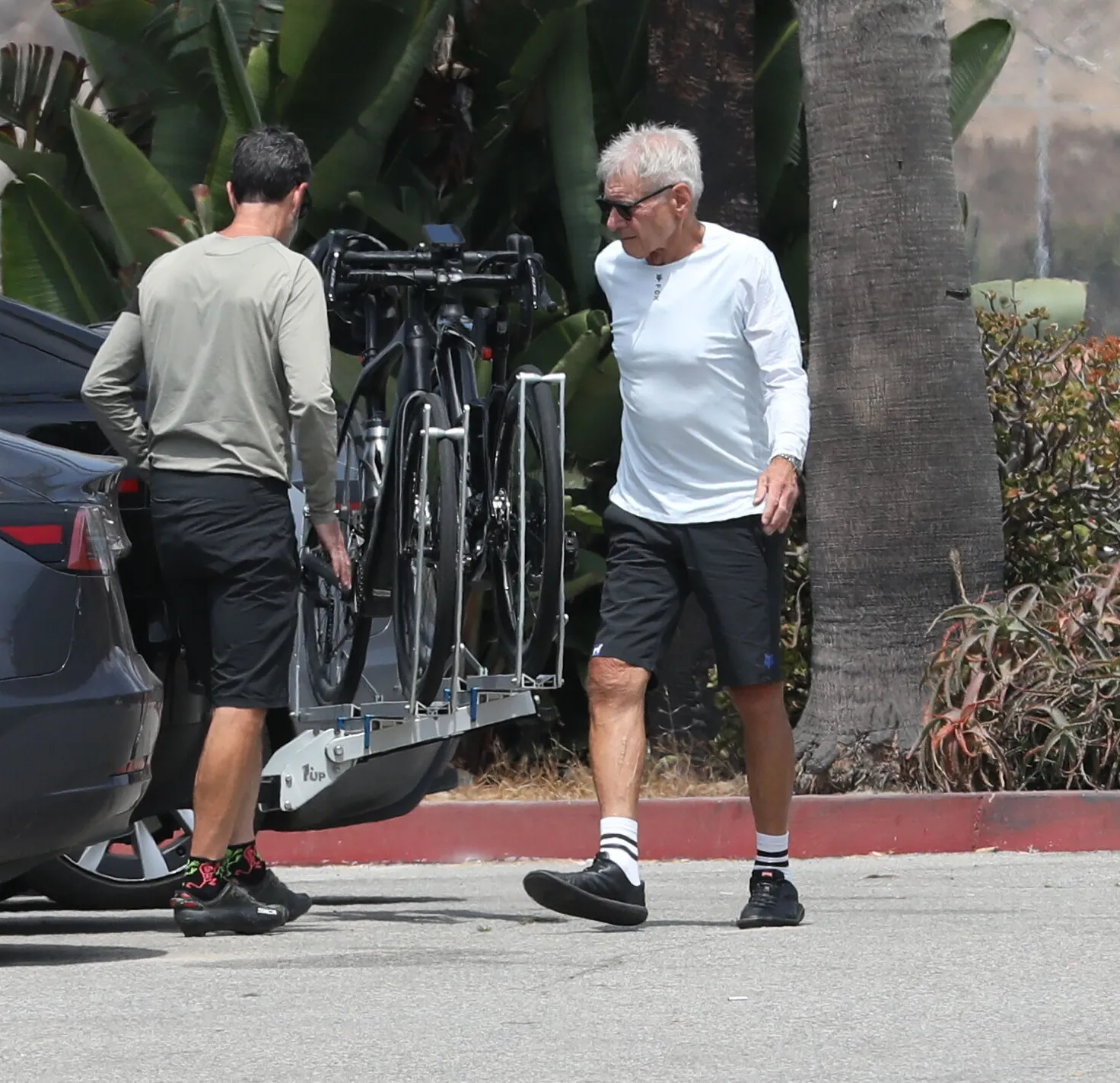 Harrison Ford walking beside a car with bikes mounted on the back.