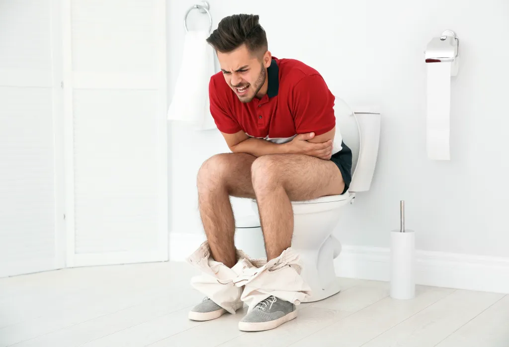 Young man suffering from diarrhea on a toilet bowl at home.