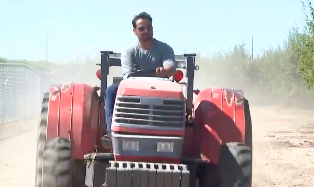Cesar Mora driving a tractor on a dirt road.