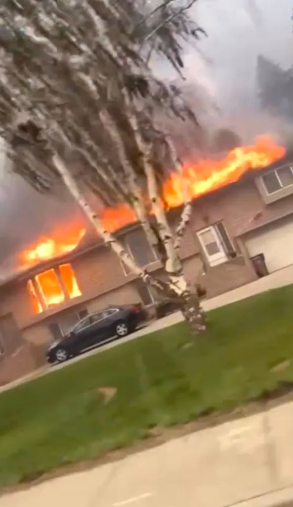 A house is engulfed in flames with bright orange fires consuming its windows and roof.