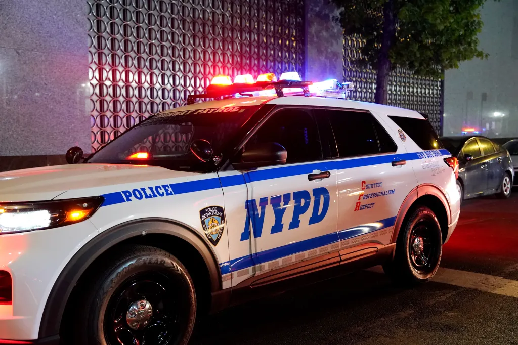 An NYPD Highway Patrol vehicle with flashing lights parked on a street at night.