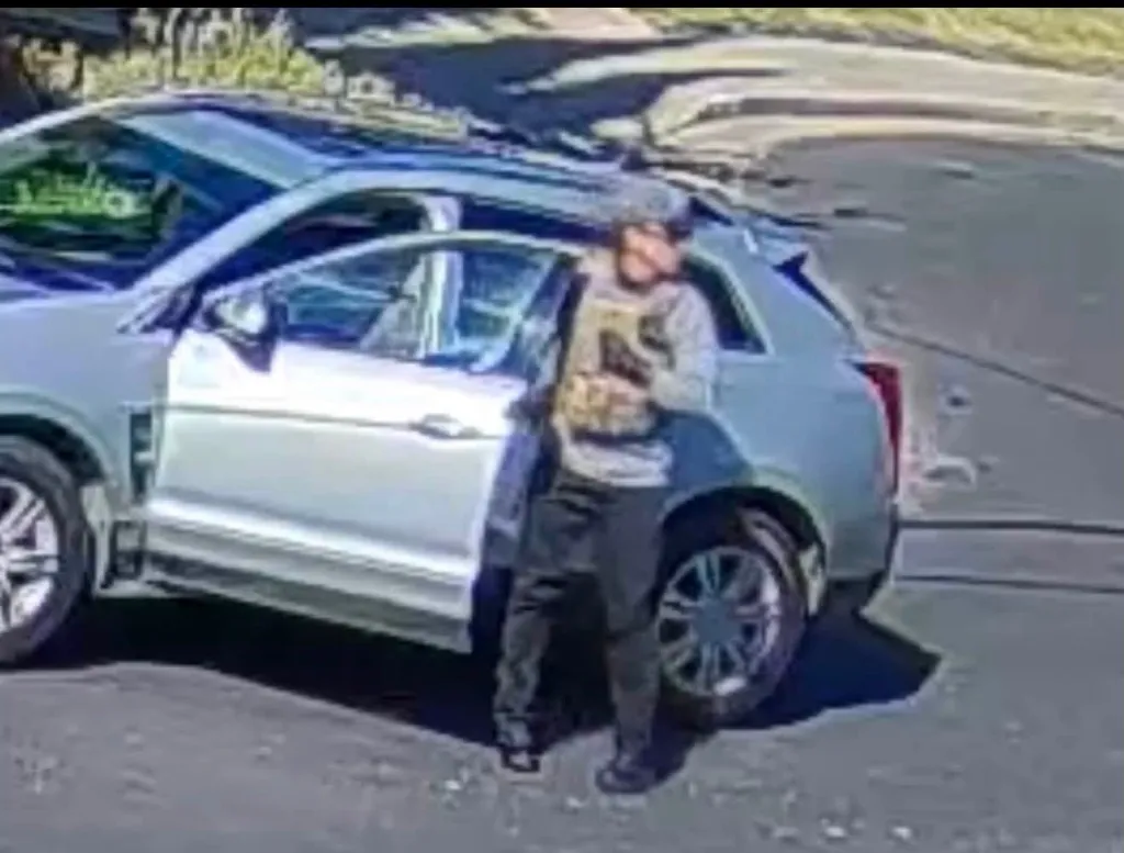 Marcos Iriarte-Valdez standing by a light-colored SUV with the driver's side door open.