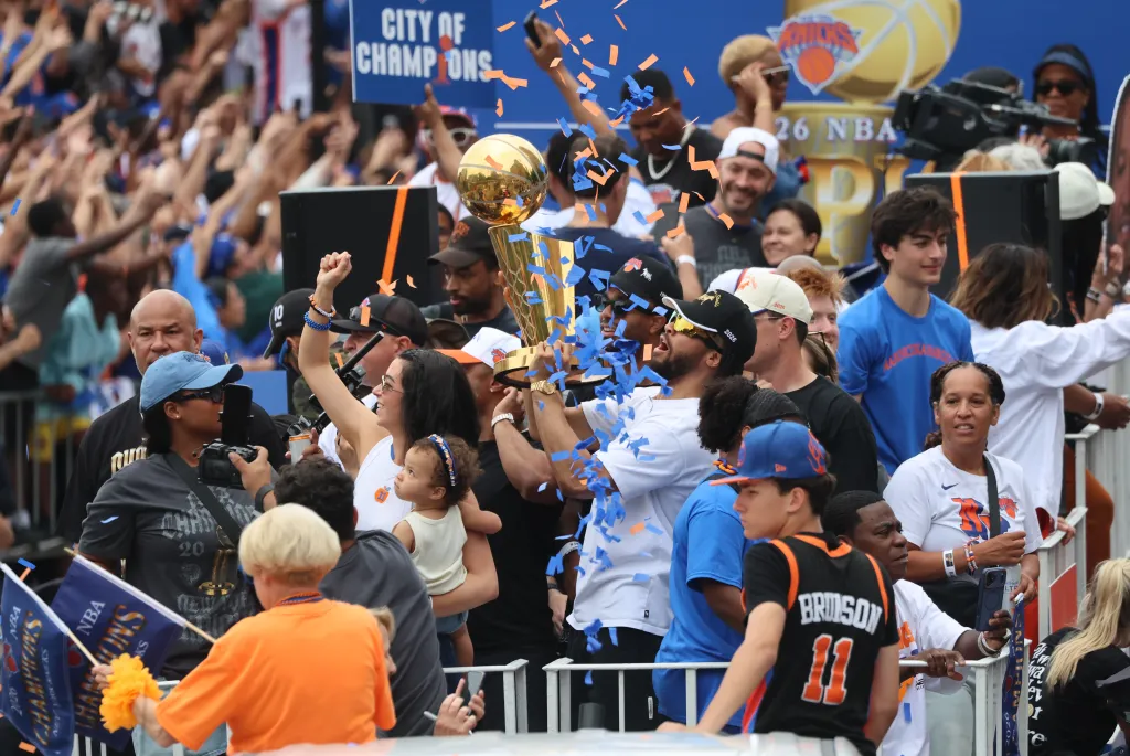 New York Knicks players and staff celebrate with the championship trophy during a ticker-tape parade.