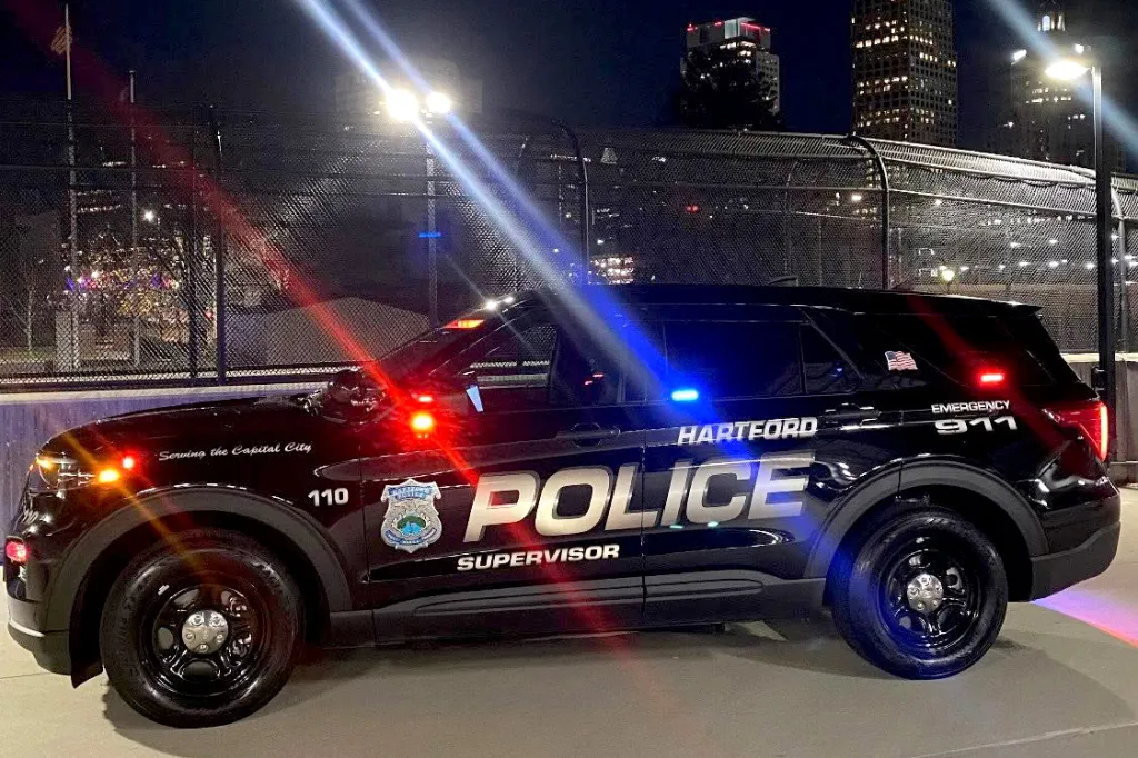 A black Hartford Police supervisor SUV with emergency lights flashing, parked at night.