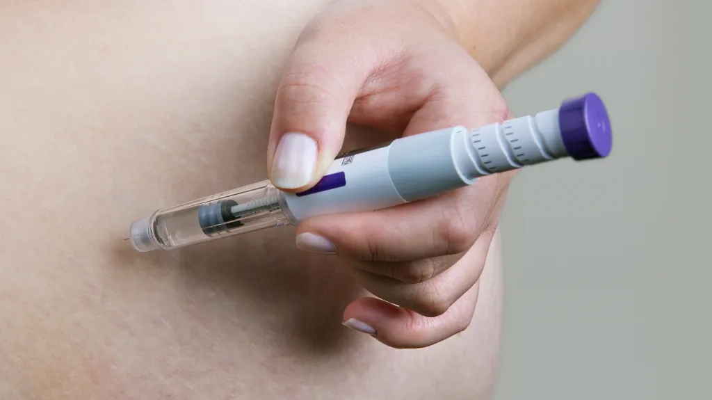 Person using an injector pen to give themselves an injection in the abdomen.