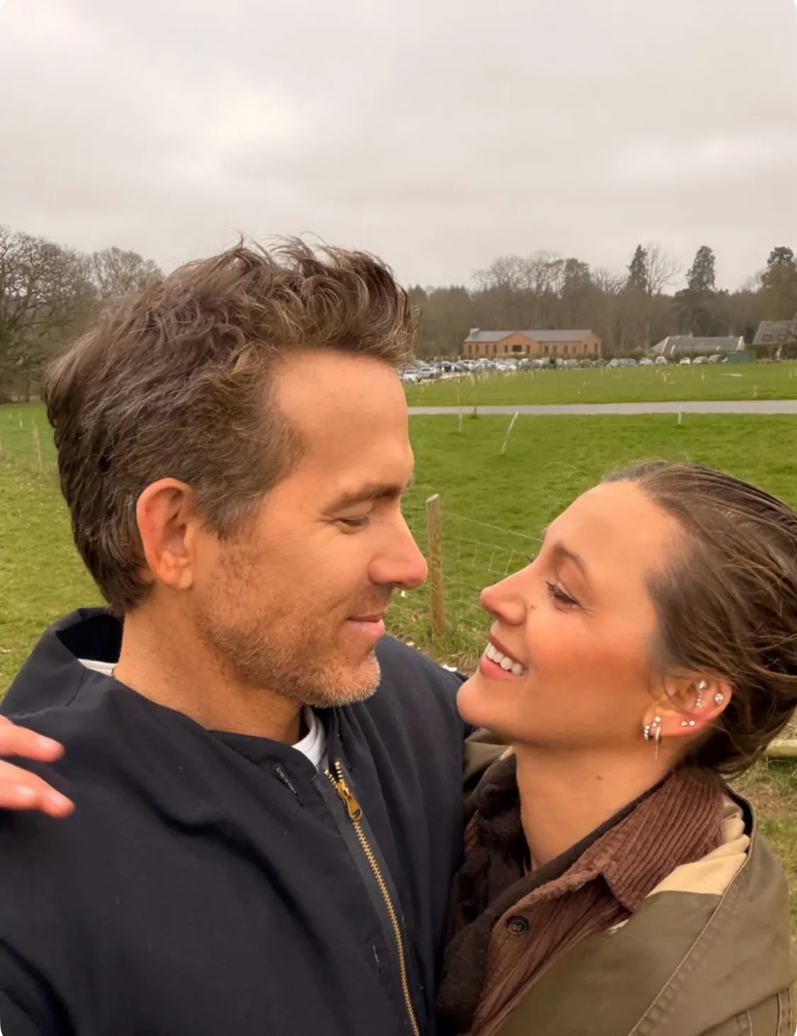 Ryan Reynolds and Blake Lively smiling at each other outdoors.