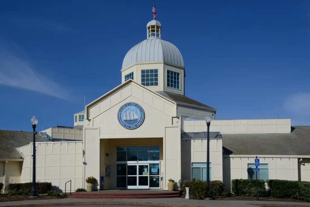 Suisun City Hall in California, a light-colored building with a large dome and a US flag on top.