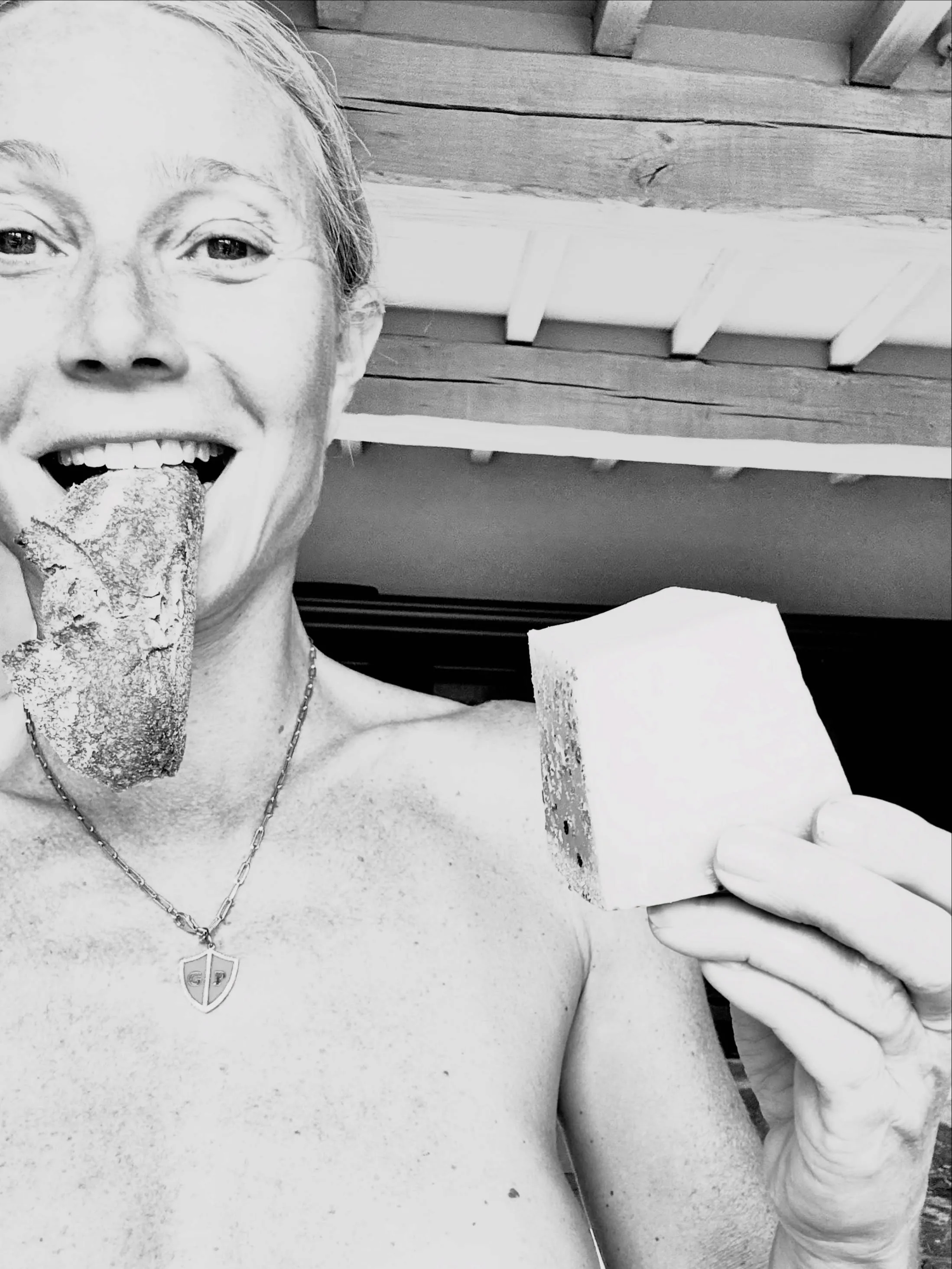 A person smiling and holding two pieces of what appears to be sourdough bread.