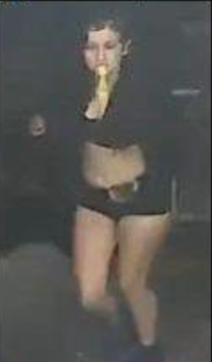 A woman in a dark outfit holding a bottle to her mouth.