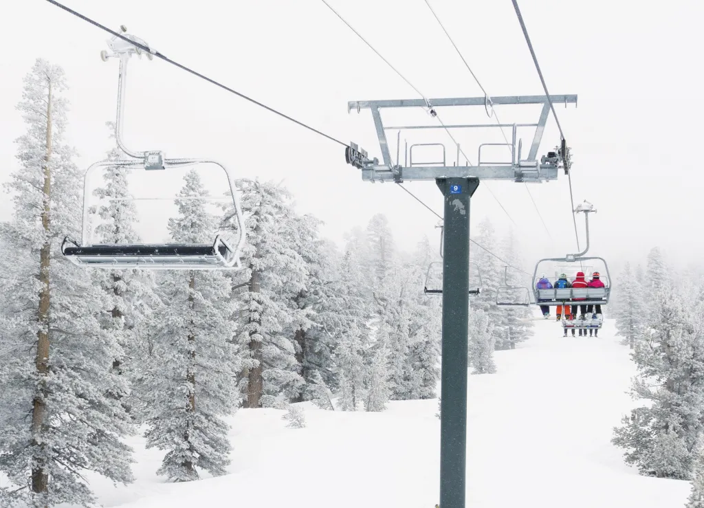 People on a ski lift at a snow-covered resort in Tahoe.