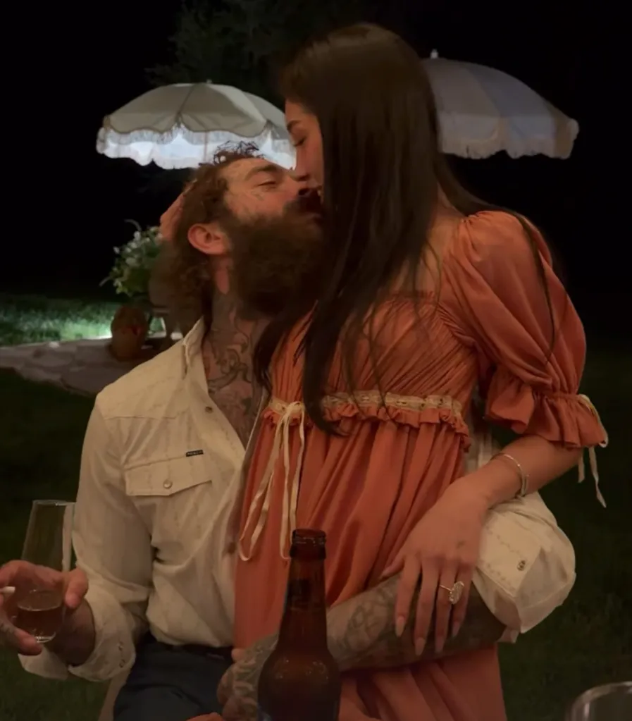 Post Malone kissing a woman wearing a peach dress.