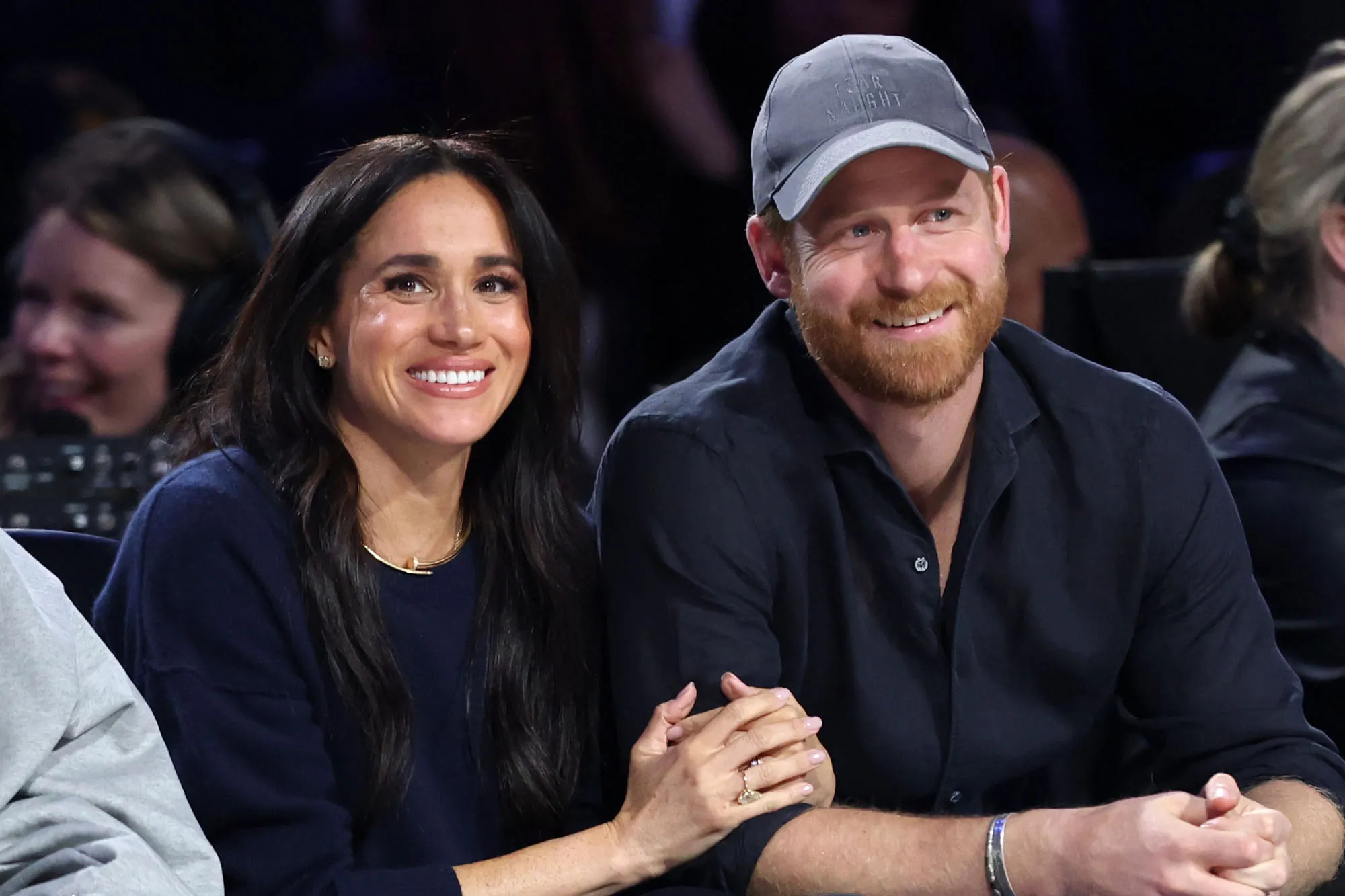 Meghan Markle and Prince Harry sitting together and smiling.