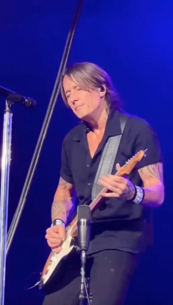 Keith Urban playing an electric guitar on stage.