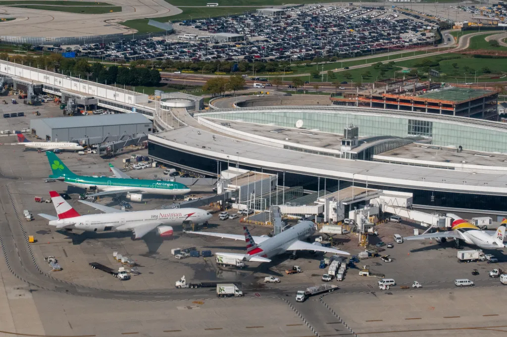Aerial view of Terminal 5 at Chicago's O'Hare Airport with Aer Lingus, Austrian Airlines, American Airlines, and Air Belgium planes parked at gates.