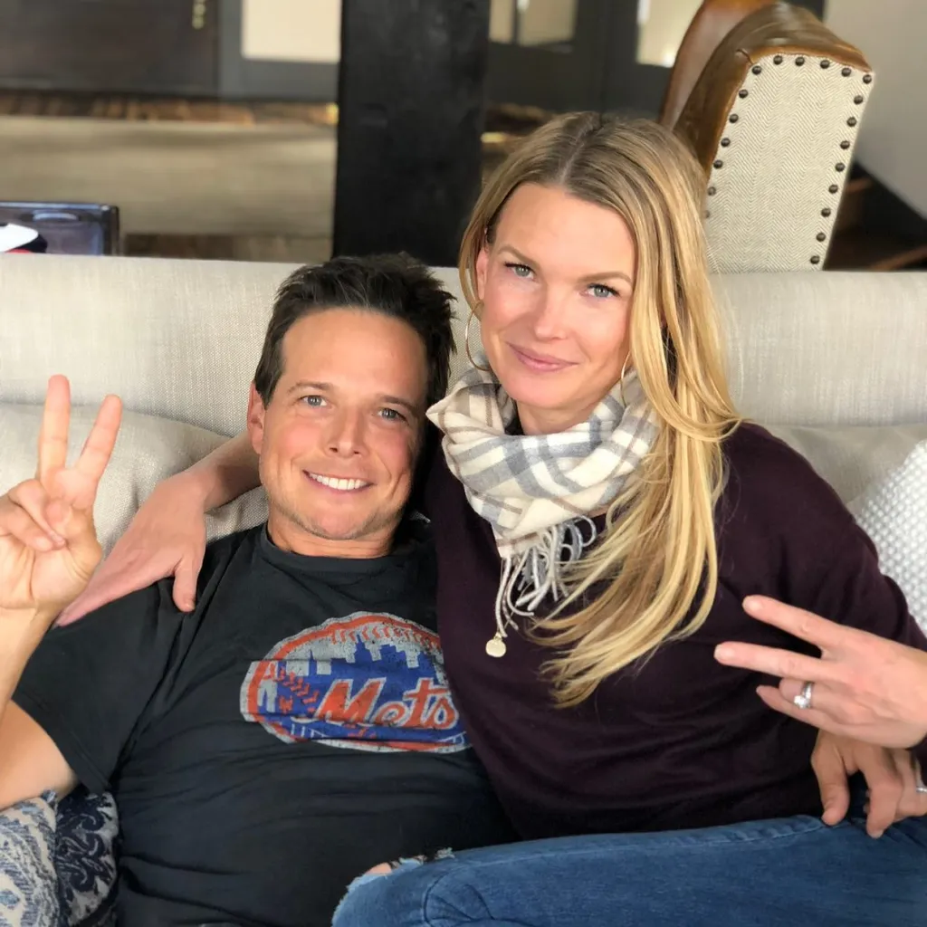 Man and woman on a couch giving peace signs.
