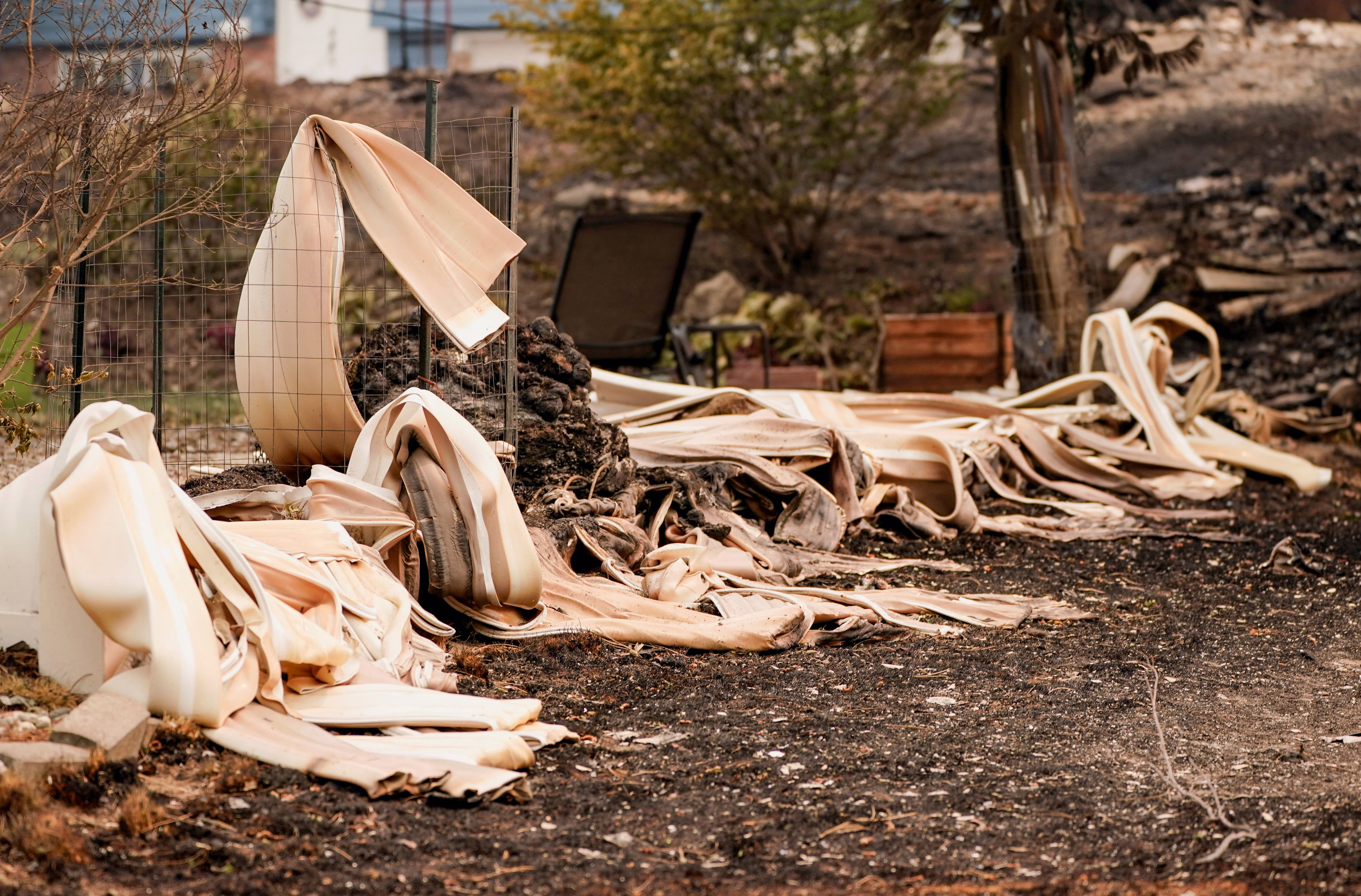 Melted siding lies outside a property damaged by a wildfire.