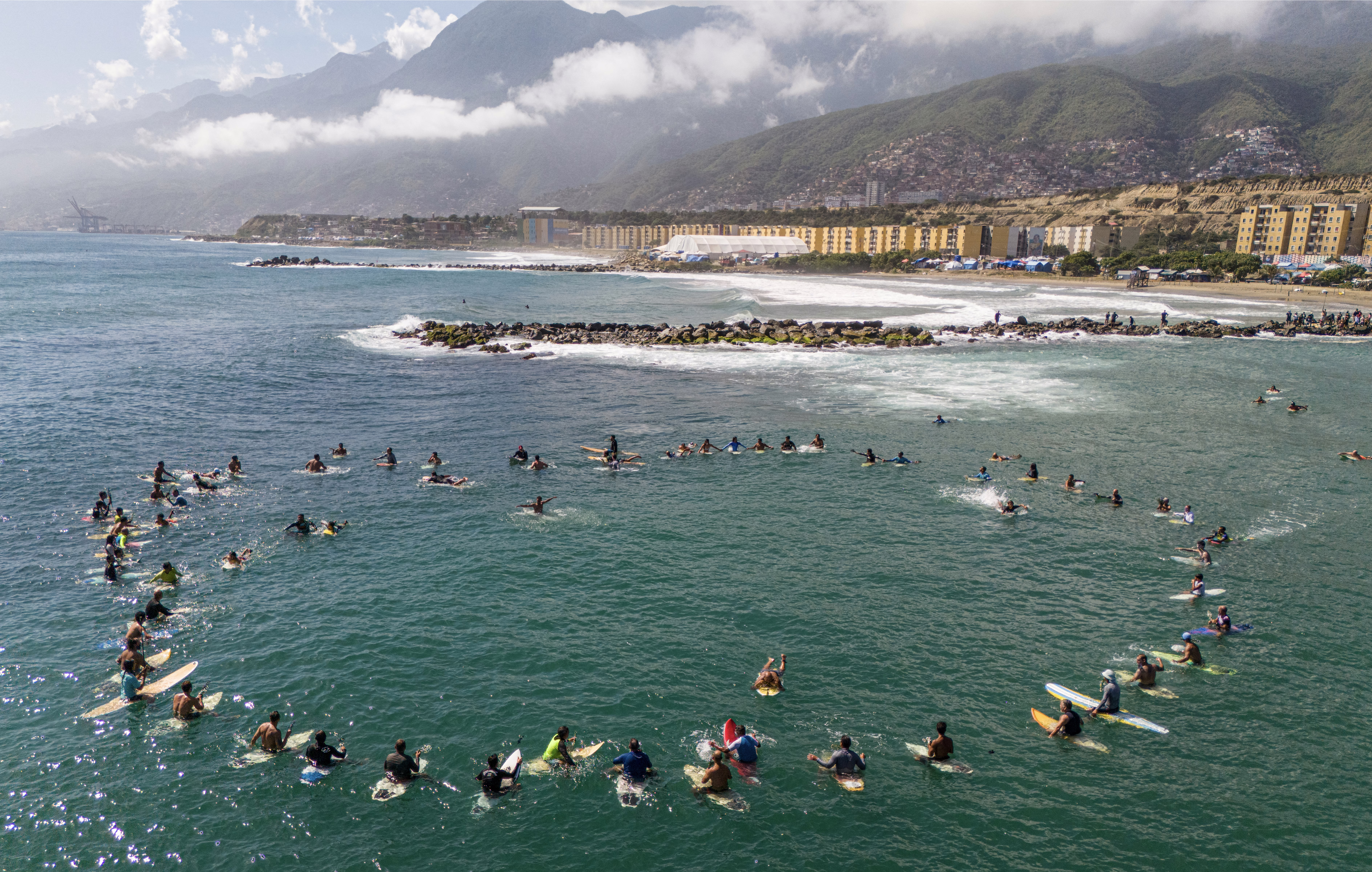 Dozens of surfers form a circle just offshore, during a tribute ceremony.