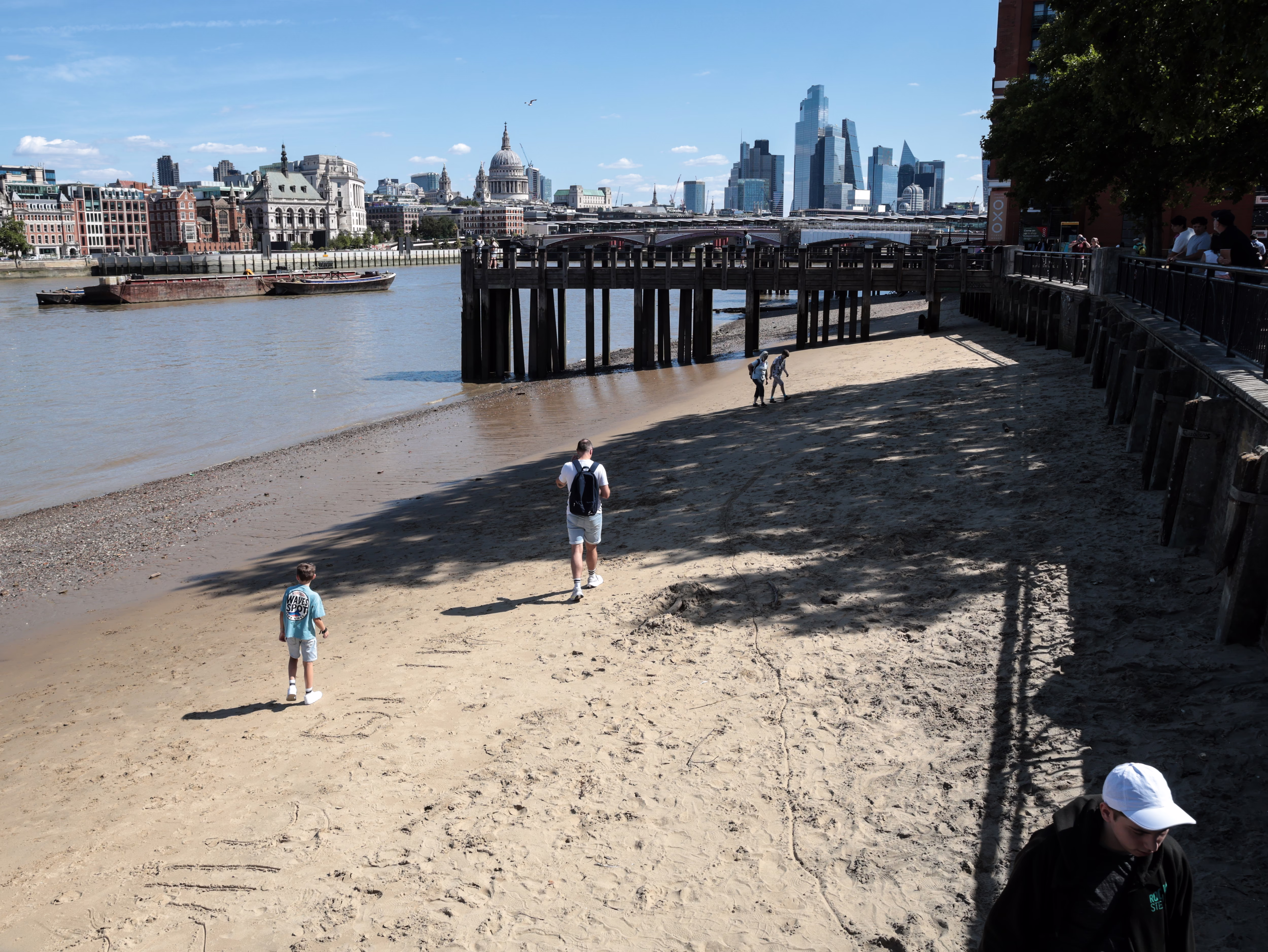People walk on a beach on the south bank of Thames River in central London.