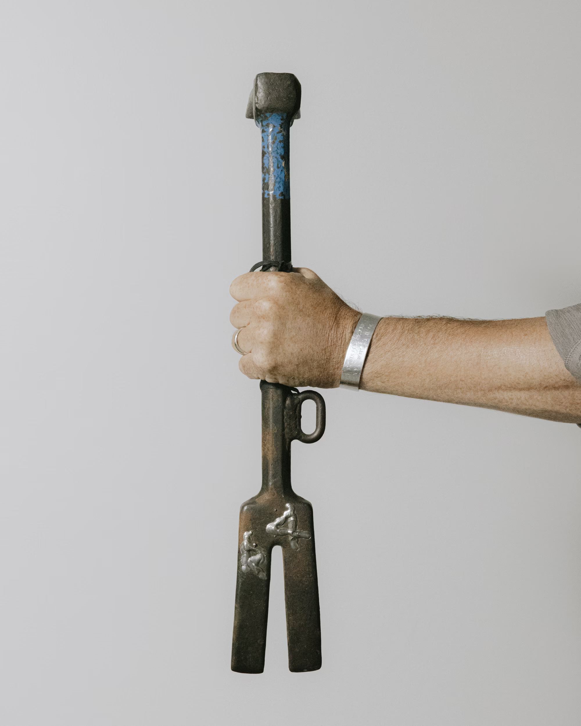photo of man's arm holding a large metal firefighting tool