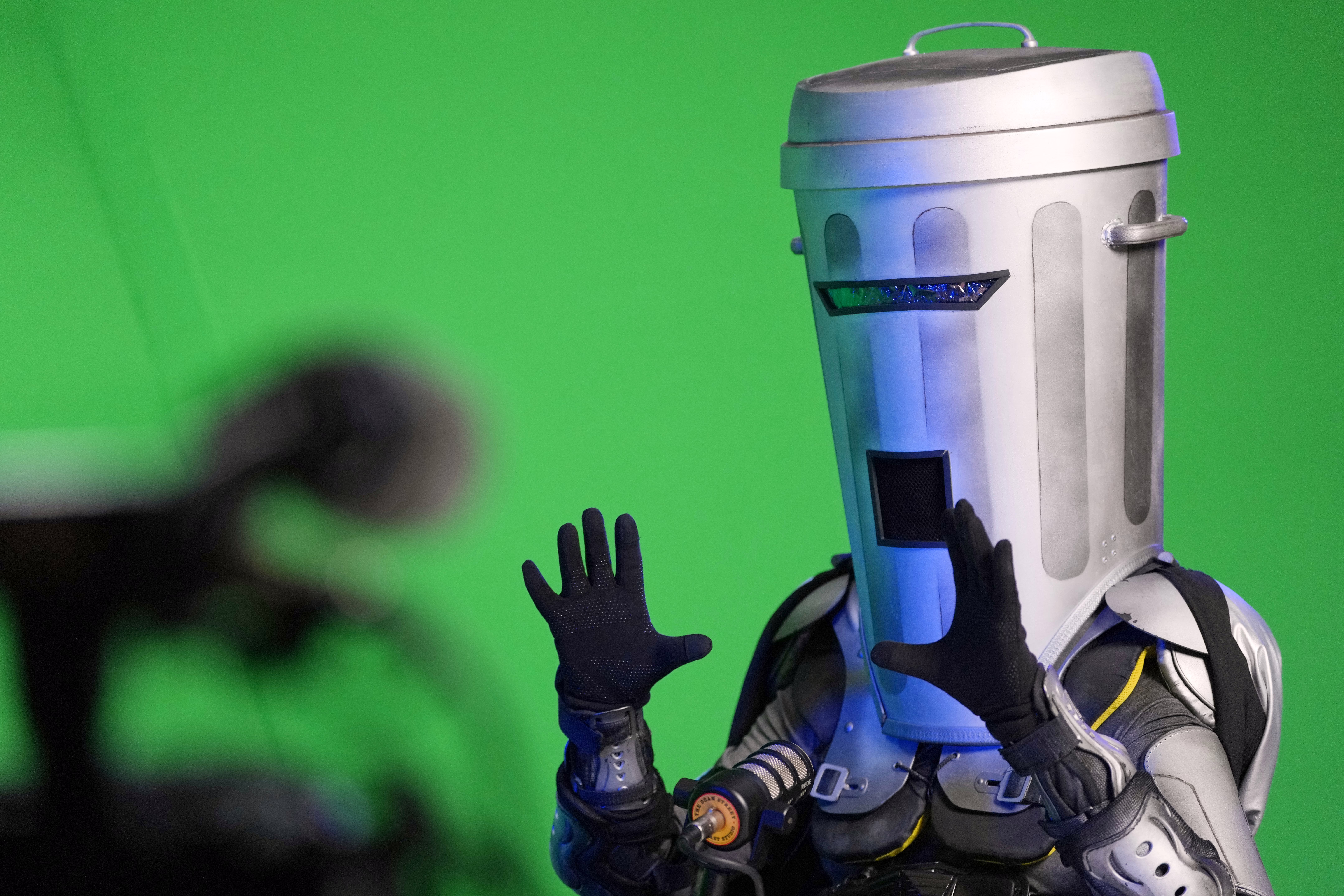 A man wearing a full-head garbage-can mask is interviewed as a candidate before an election.