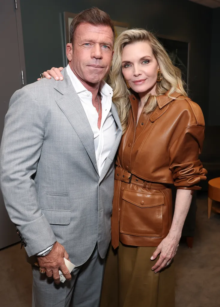 Taylor Sheridan, in a light grey suit and white shirt, and Michelle Pfeiffer, in a brown leather jacket and khaki pants, at 