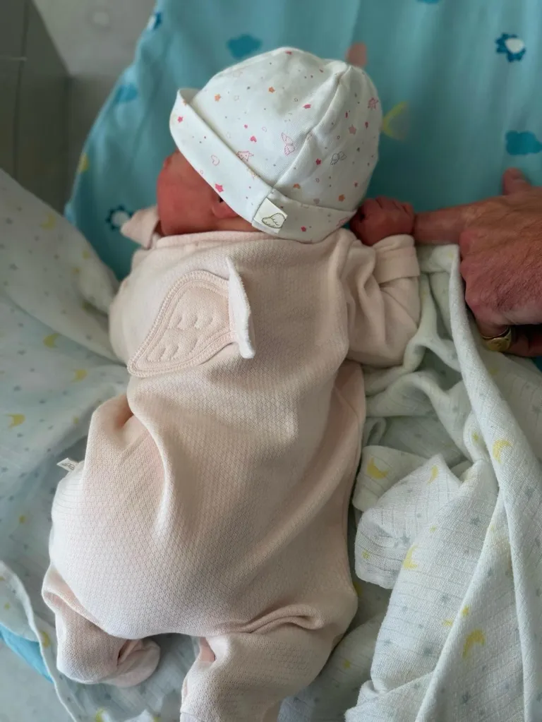 Baby Adelaide Brooksbank I a white baby grow and white hat with pink stars.