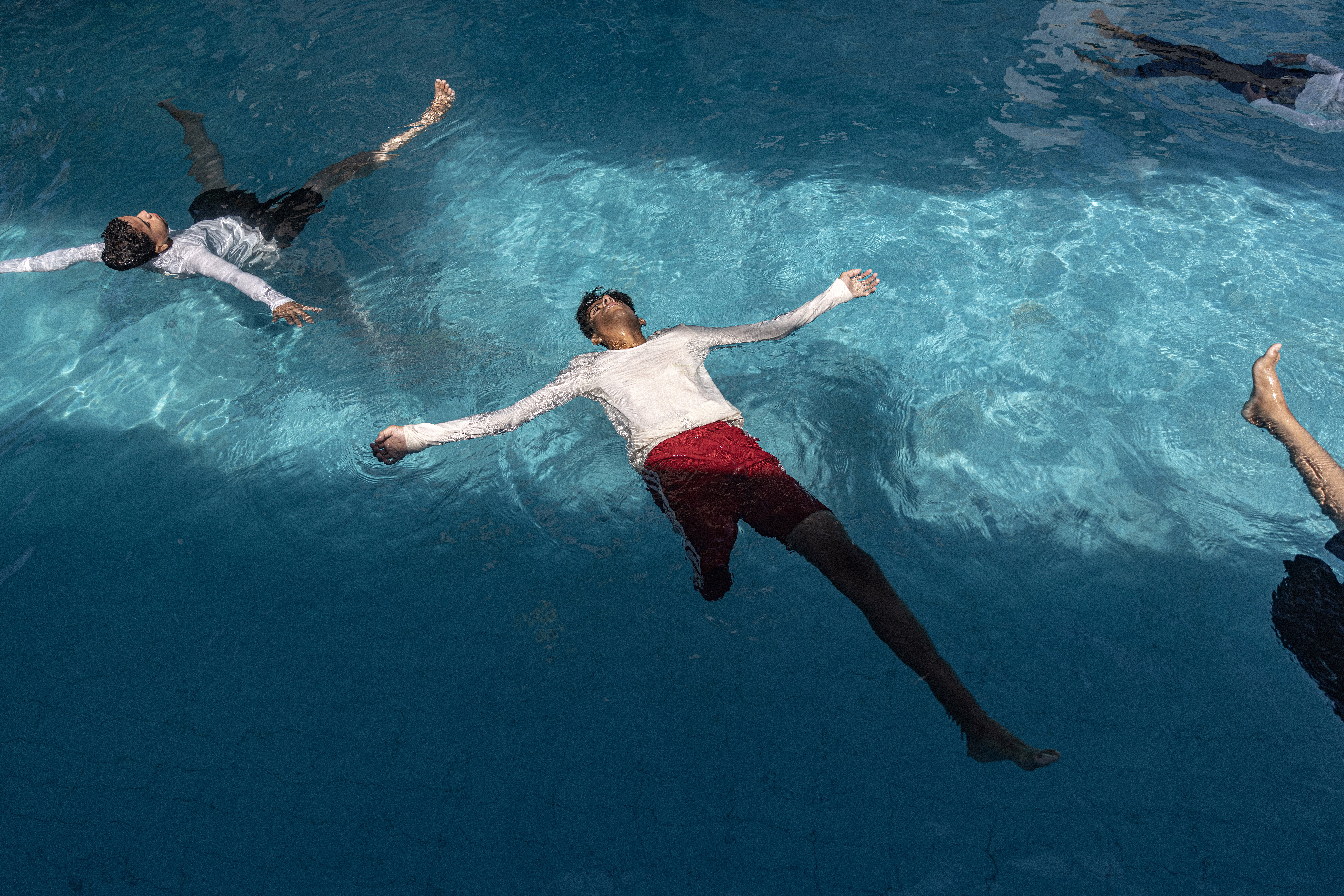Several children float in a swimming pool during a training session.