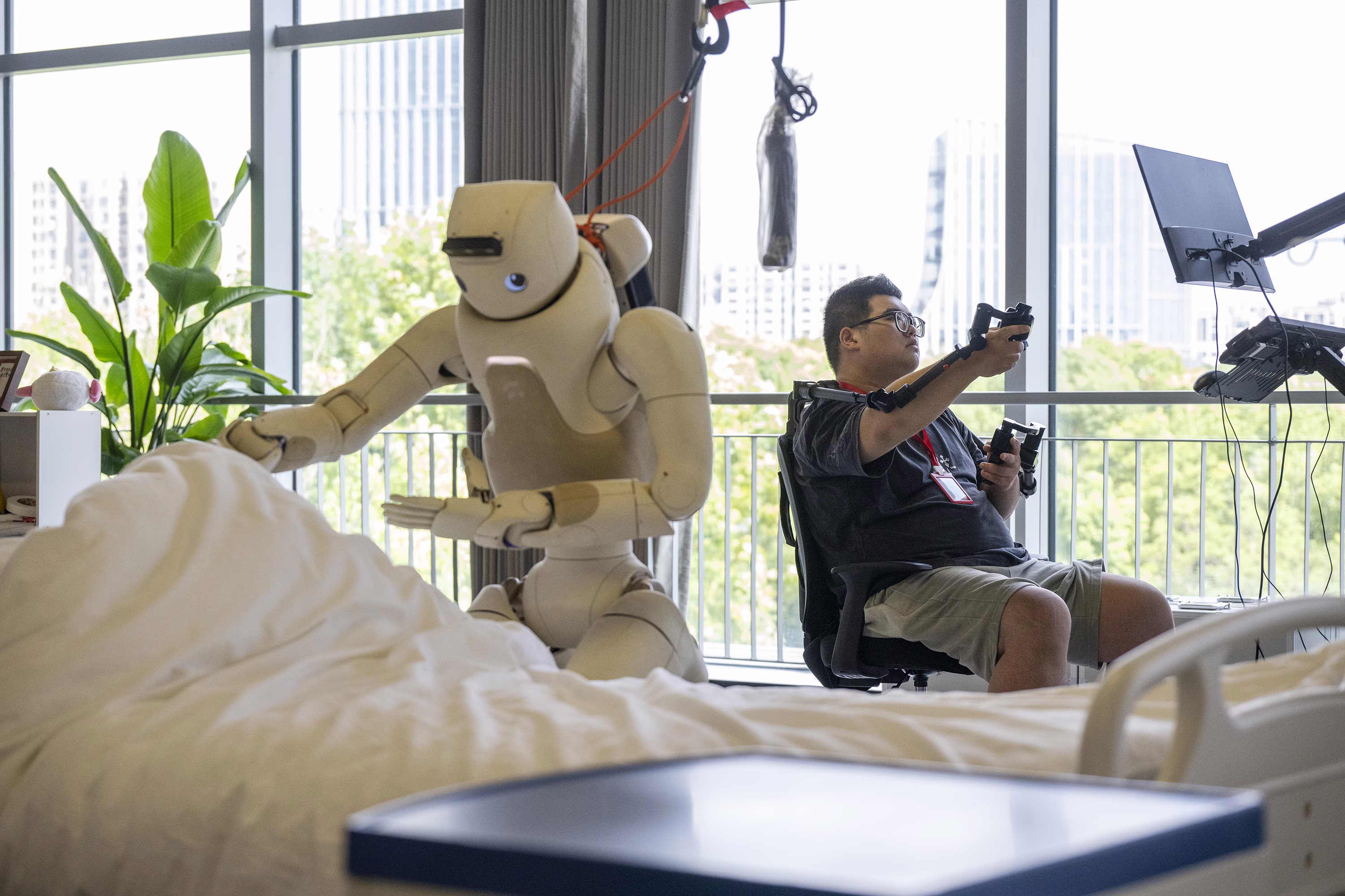 A person uses controllers to interact remotely with a humanoid robot.