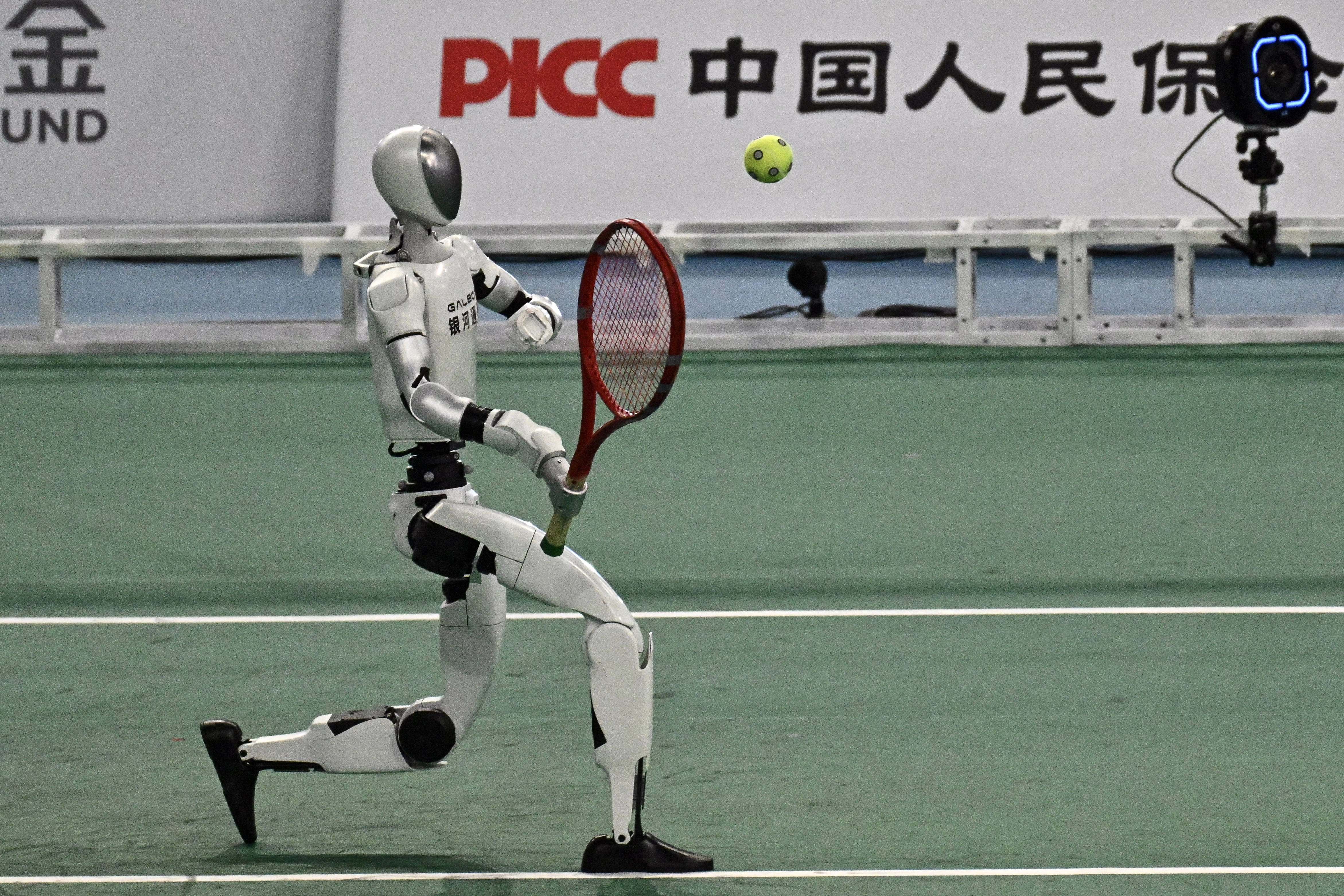 A humanoid robot returns a ball during a tennis match.