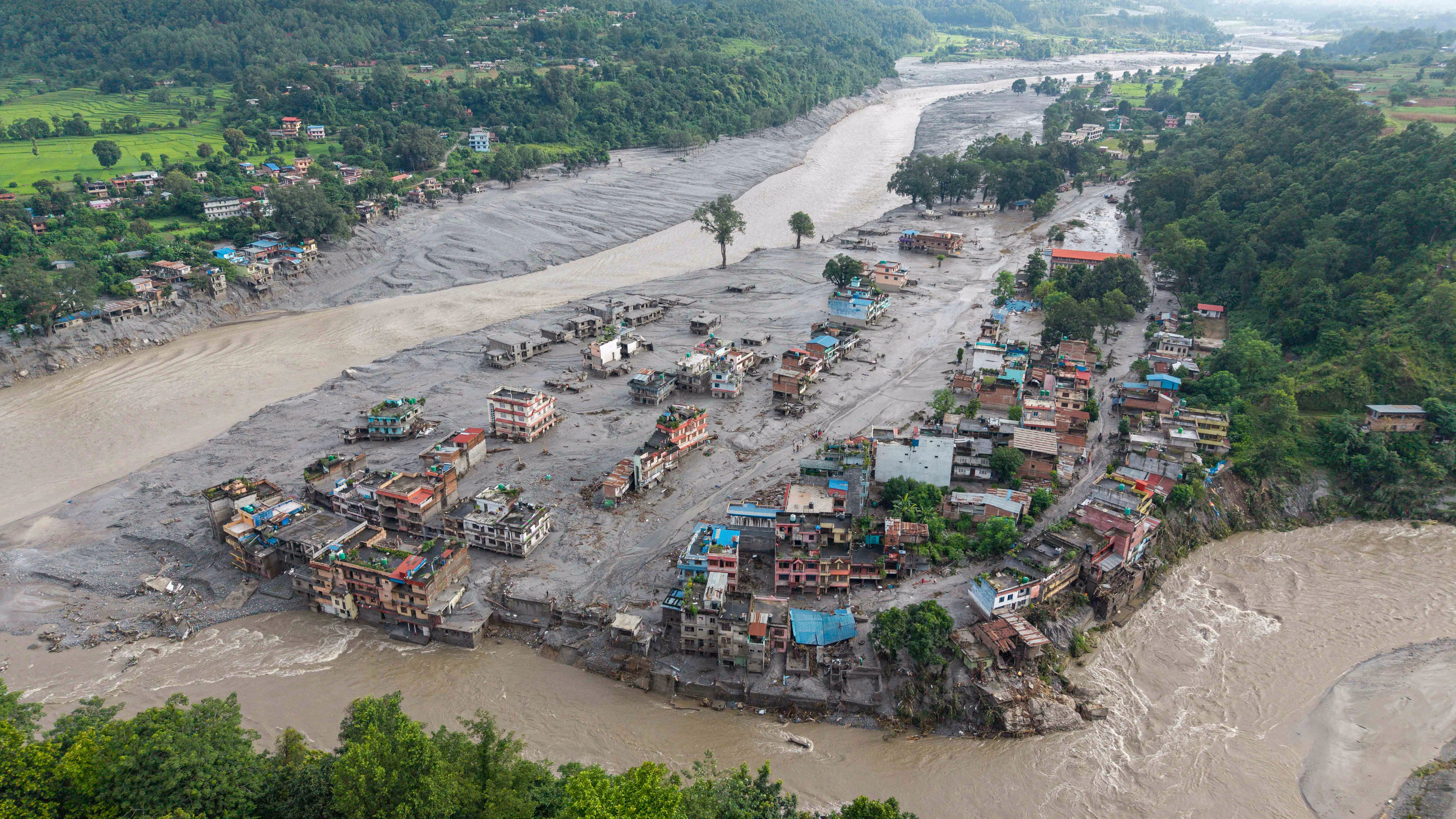 An aerial view shows houses lying deluged in sludge alongside a river, after a powerful flash flood.