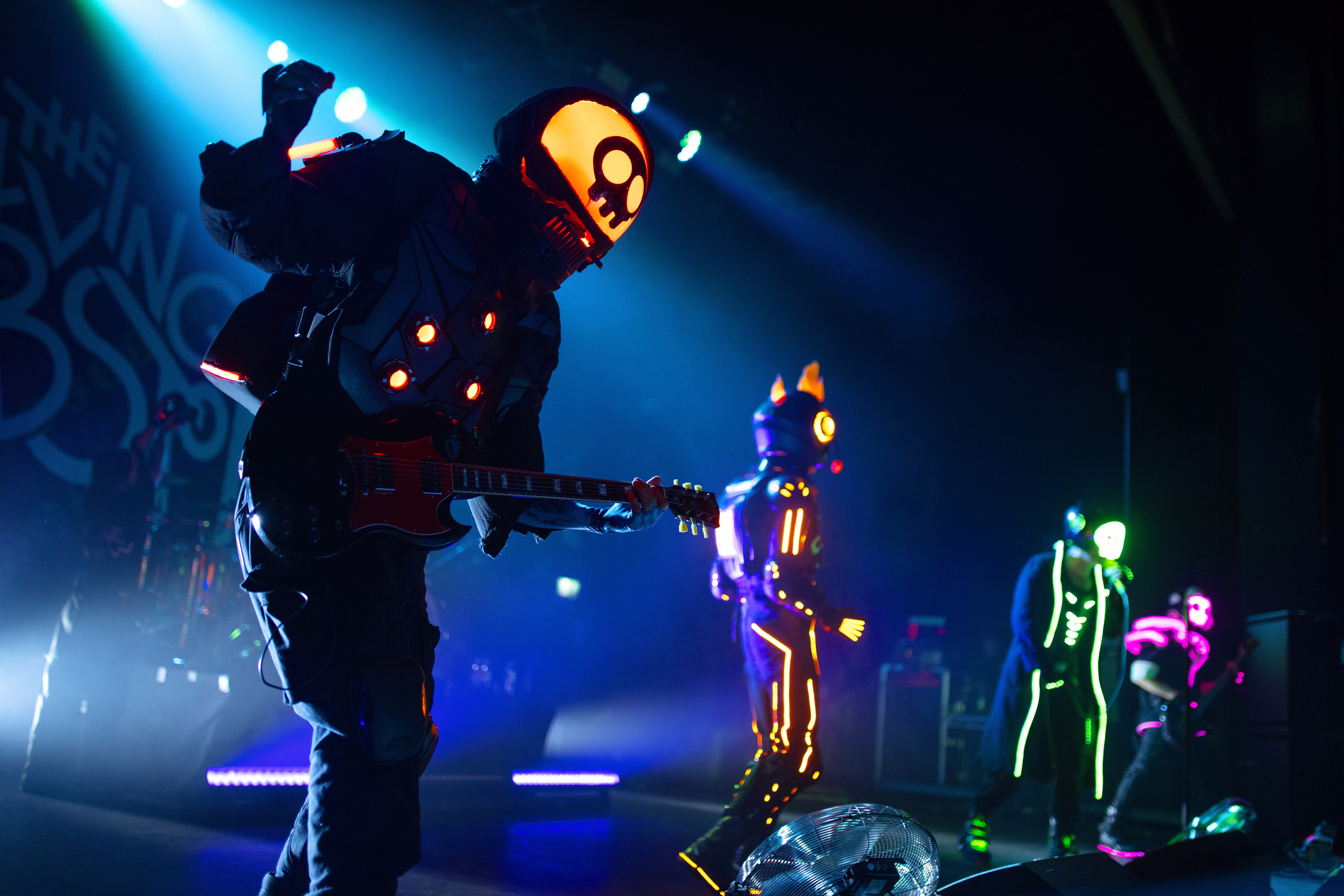 A band wearing illuminated costumes performs onstage.