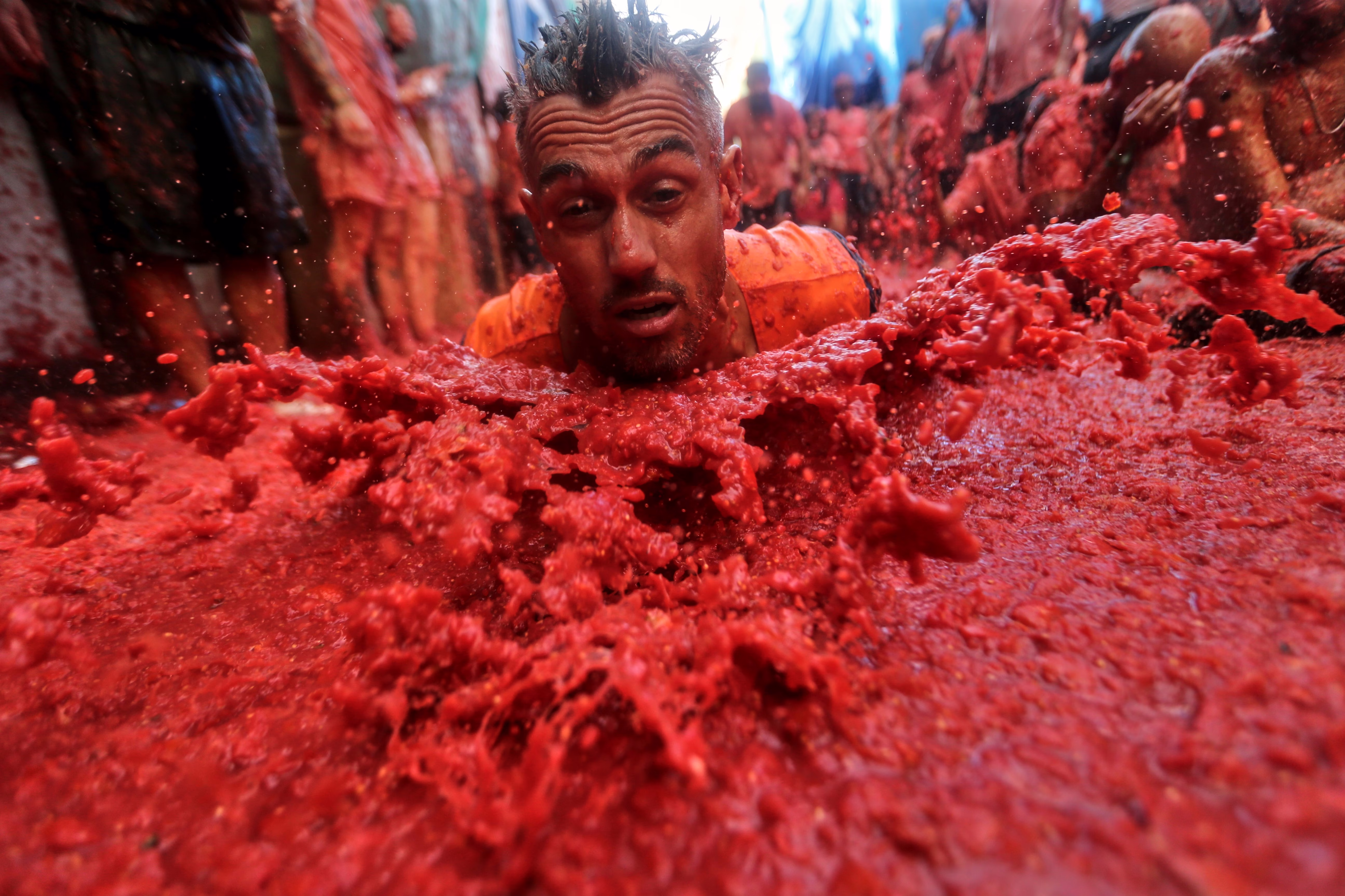 A man splashes into a thick pile of smashed tomatoes.