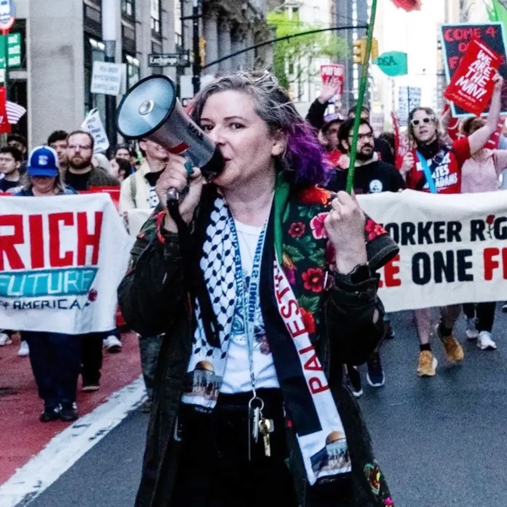 DSA labor coordinator Olivia Killingsworth with purple-dyed hair uses a megaphone to lead a protest.