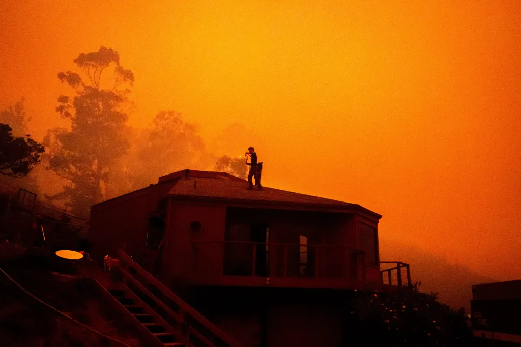 Sage Harvey tosses a rope off the roof of his house as the Plaskett Fire approaches in Big Sur, Calif.