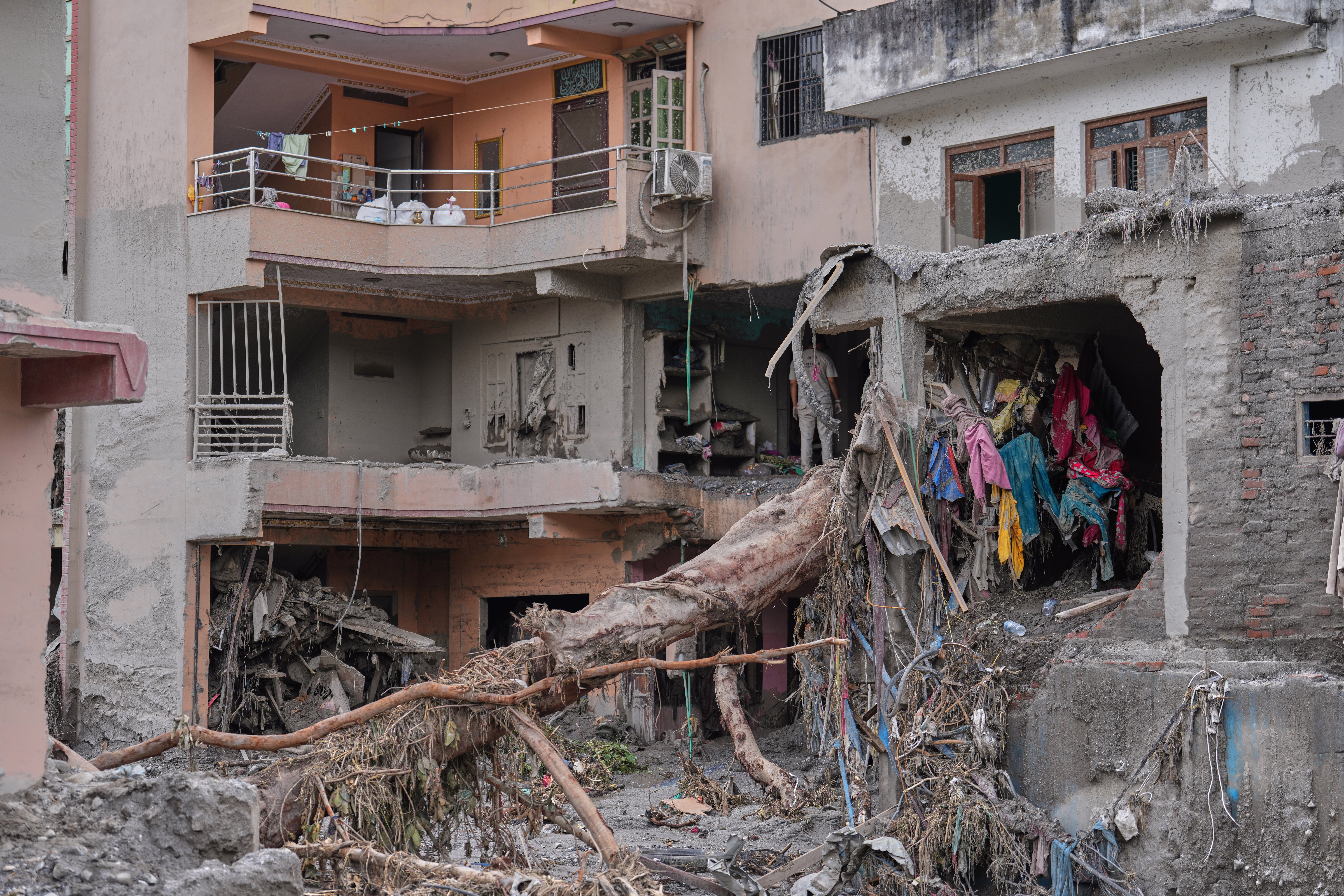 Flood-damaged homes filled with mud and debris, including a downed tree