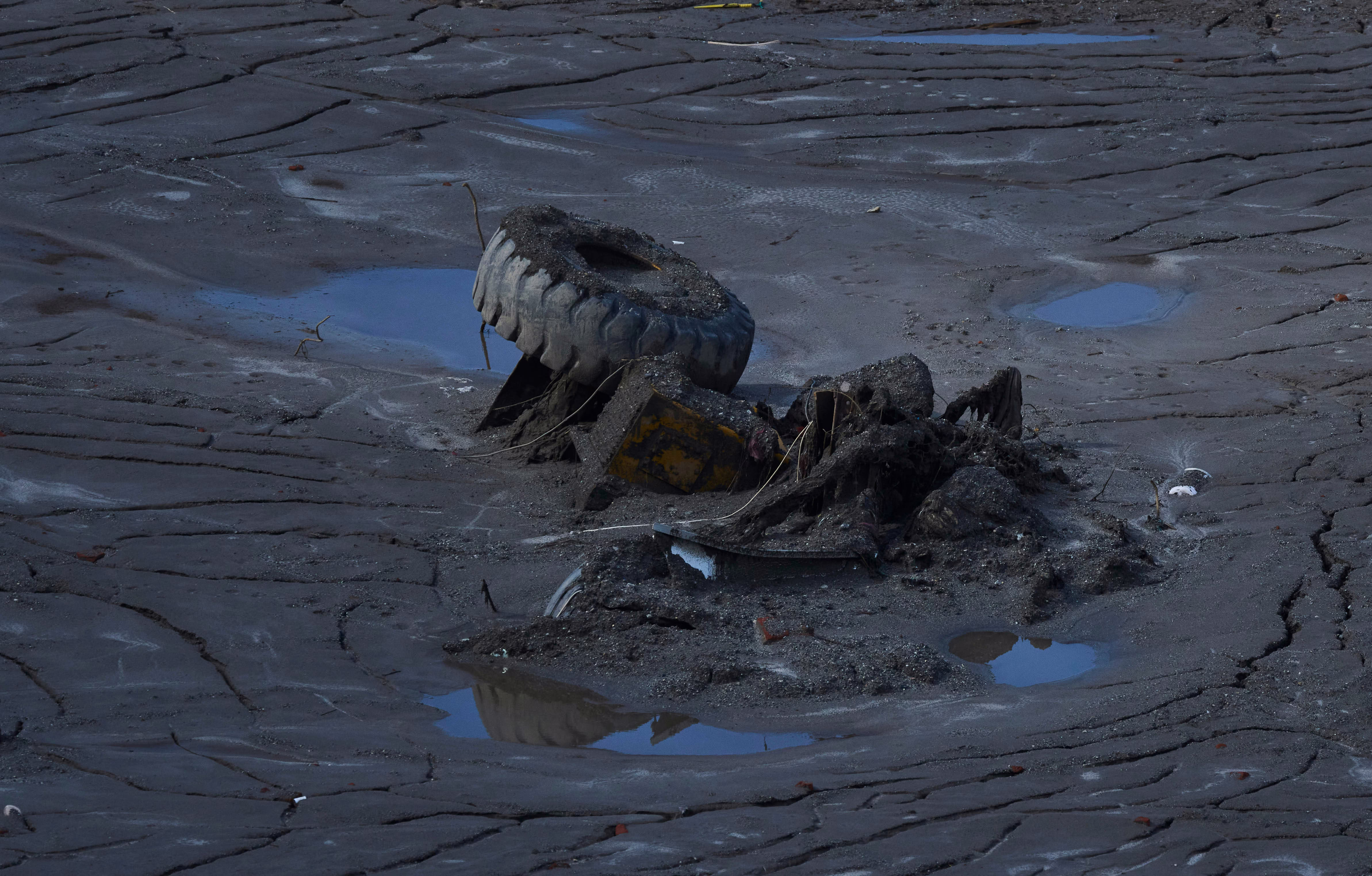 A partially-buried truck is seen in thick mud.