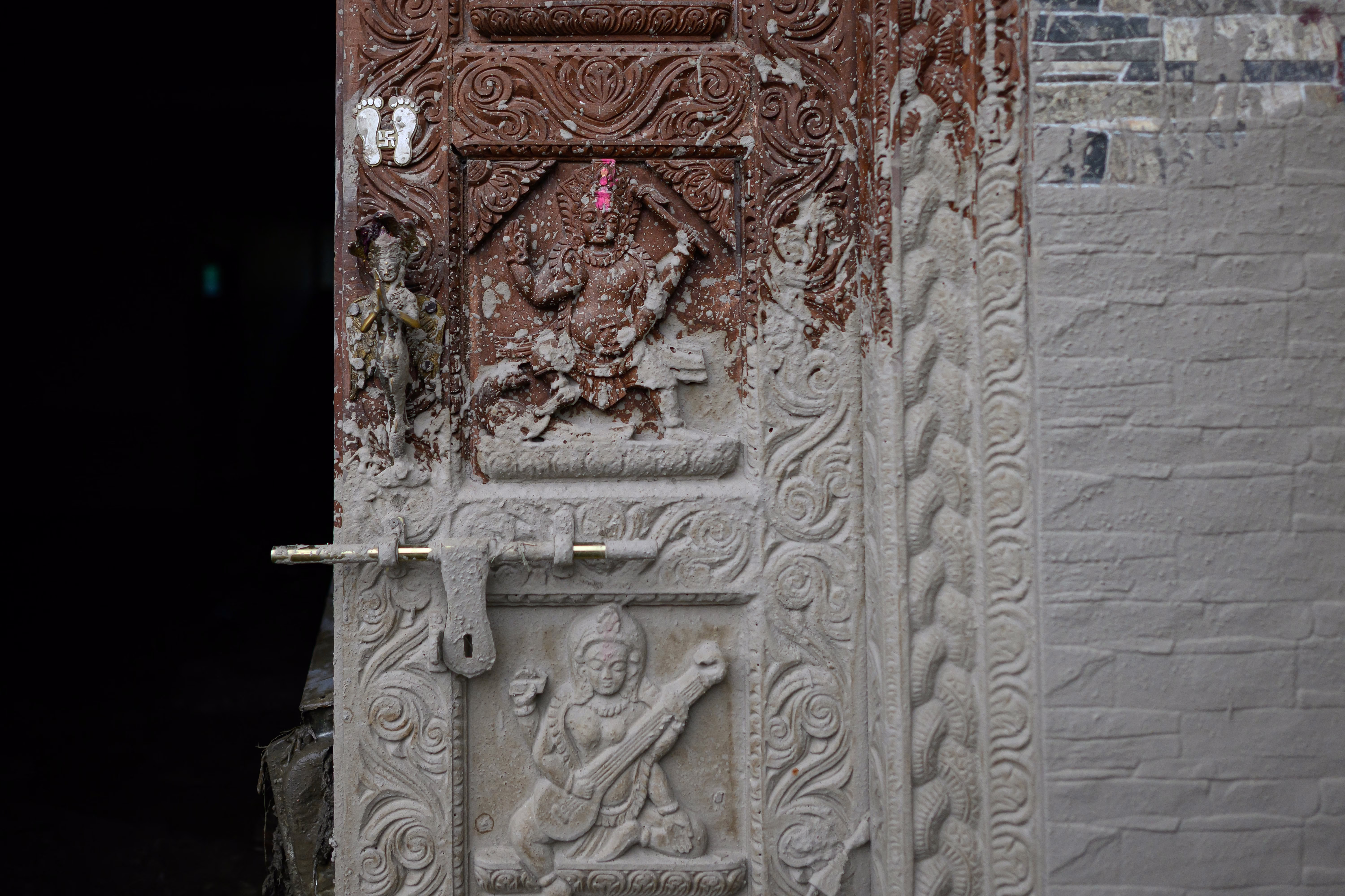 Splashed mud dries on the carved wooden door of a house.