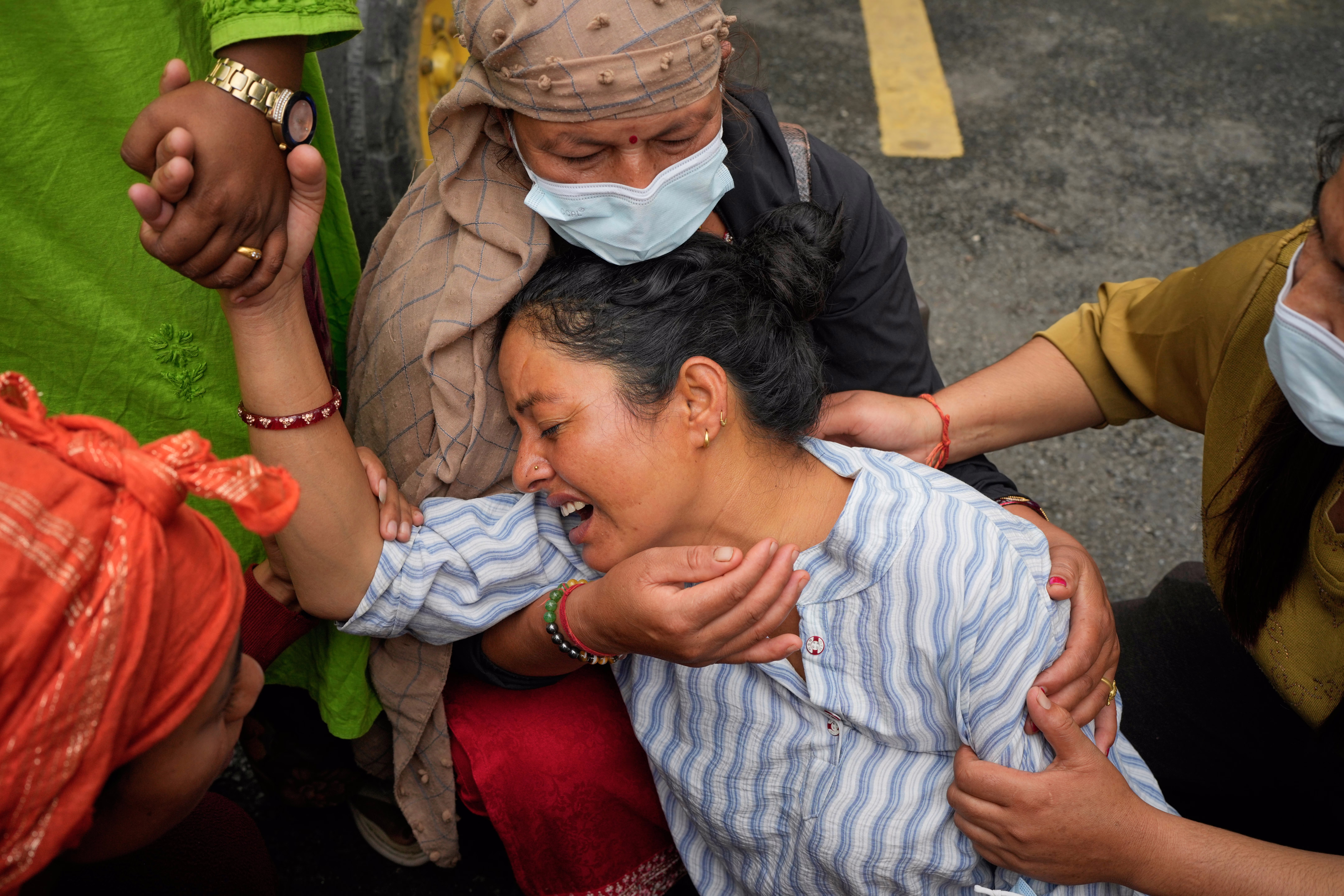 A mother cries during a mass burial, consoled and held by several relatives.
