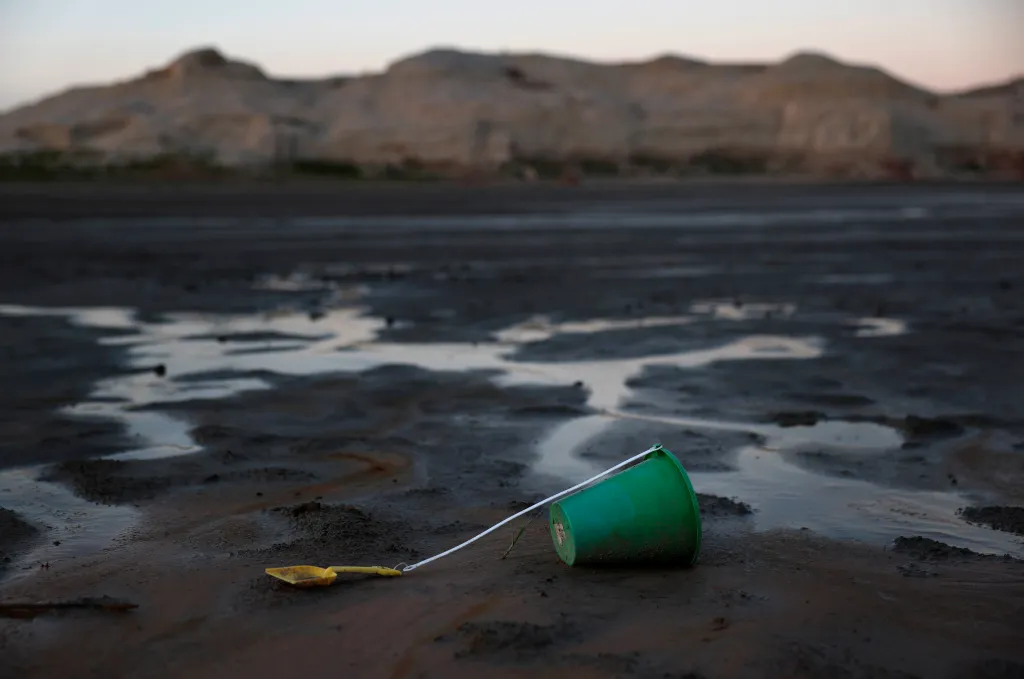 A green bucket lies on muddy, dry ground, which was previously underwater at Lake Powell.