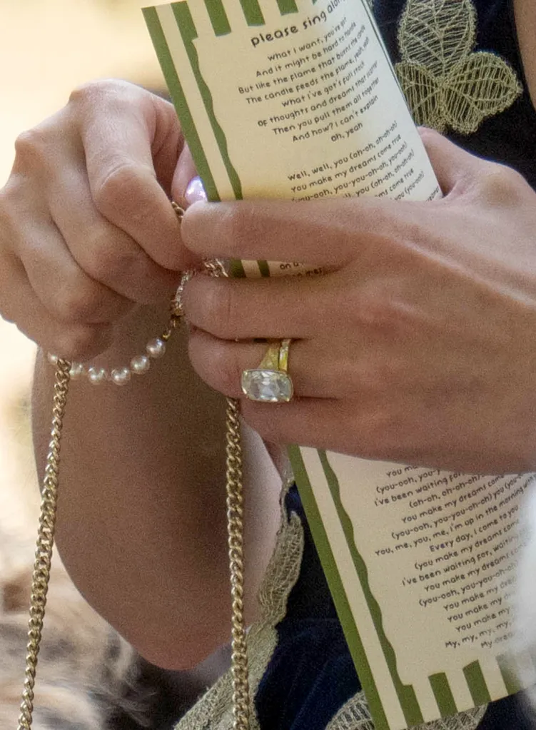 Close-up of a person's hands holding a song sheet with lyrics that begin 