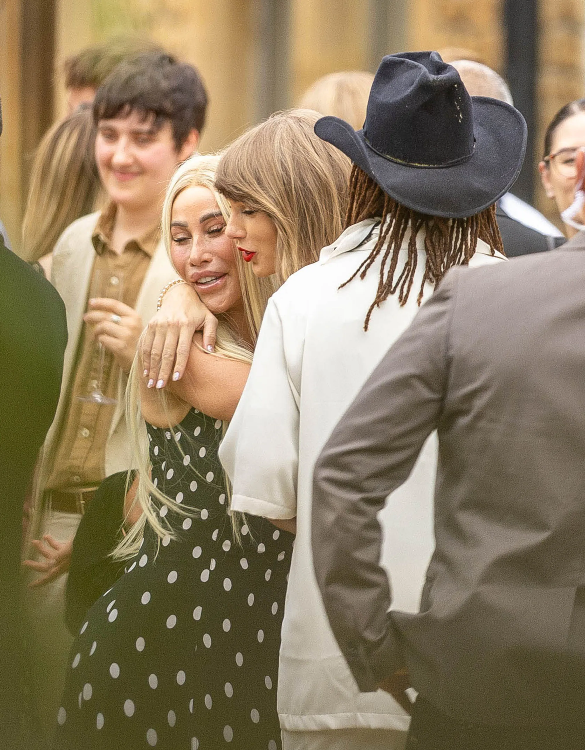 Taylor Swift hugging another woman in a polka-dotted dress at a wedding.