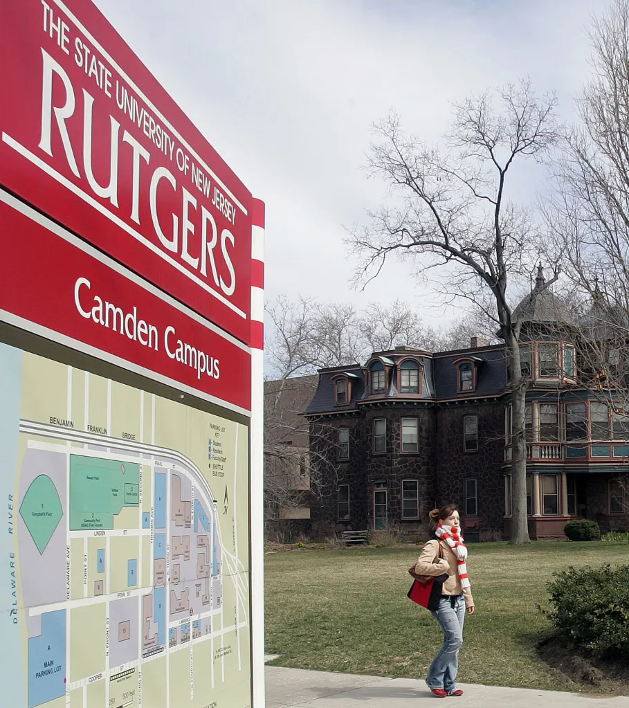 A student walks past a Rutgers University Camden Campus information board.