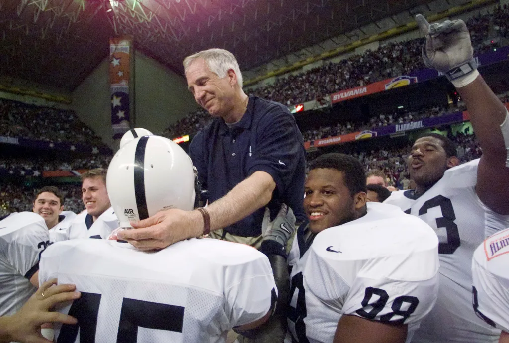 Jerry Sandusky touches defensive back Brandon Scott's helmet while he is carried by Jason Wallace and other players after the Alamo Bowl.