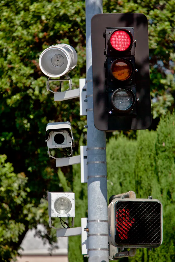 A red light traffic camera system mounted on a pole with a red traffic light and a 