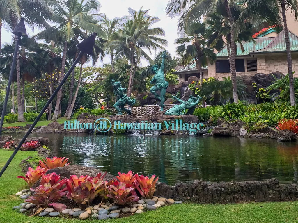 A Hilton Hawaiian Village Waikiki Beach Resort sign in an artificial lake.
