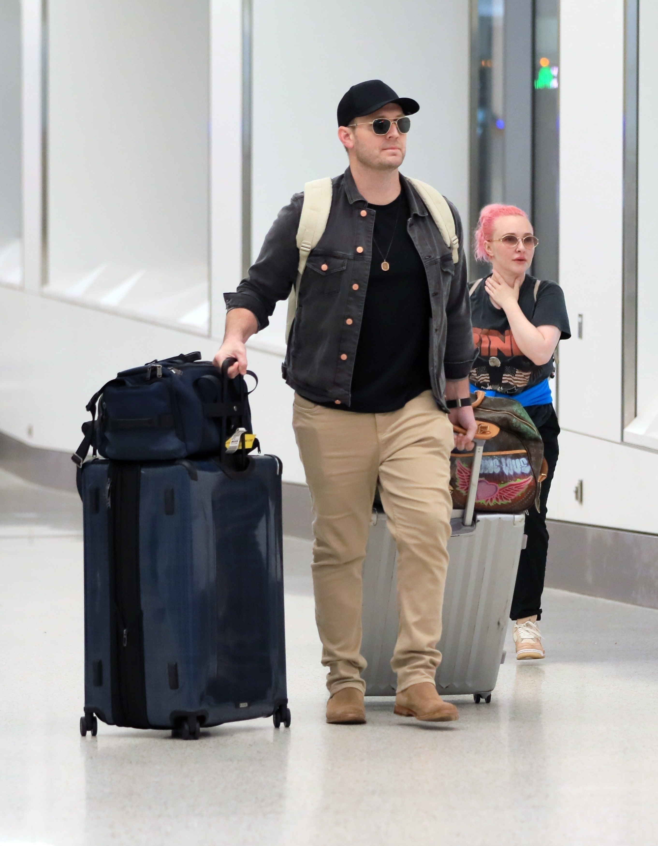Hayden Panettiere with pink hair and Brian Hickerson at LAX, both wearing sunglasses, with luggage.