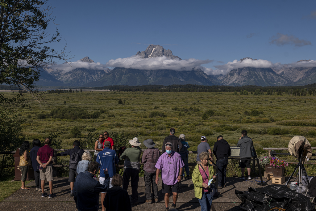 Tourists outside the Jackson Lake Lodge in Moran, Wyoming, with mountains in the background.