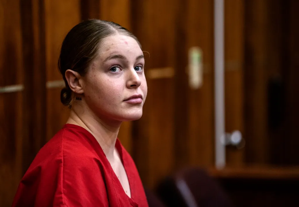 Courtney Clenney, wearing a red top, looks toward the camera during her detention hearing.