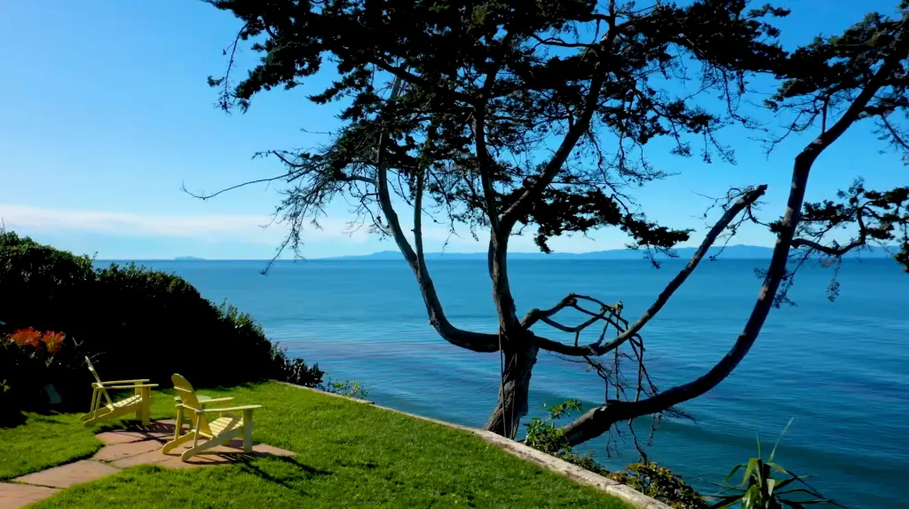 The property at 2339 Edgewater Way in Santa Barbara, showing two yellow Adirondack chairs on a grassy bluff overlooking the ocean.
