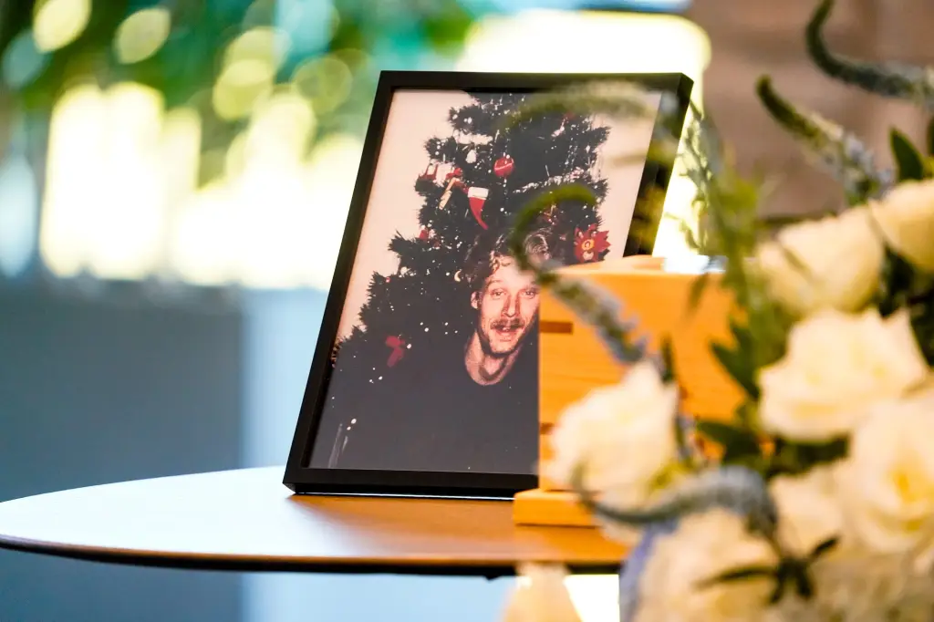 A framed photo of Allen Livingston is displayed next to his remains, with flowers nearby.